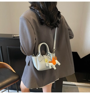Détail du sac seau en cuir grainé avec breloque cheval et fermoir pivotant doré chic