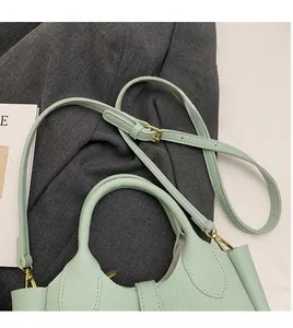 Detail of mint green lychee grain leather bucket bag with golden hardware and long strap