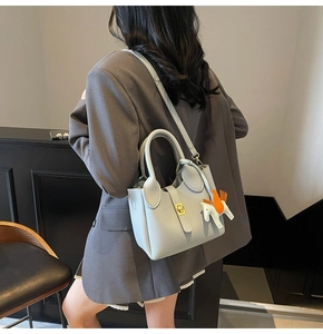 Détail du sac seau en cuir bleu litchi avec boucle dorée et breloque cheval