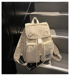 Detail view of cream nylon backpack with buckle flap and double front zipper pockets