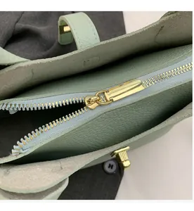 Detail of light green litchi texture leather bag with smooth gold metal zipper