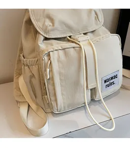 Detail of beige nylon backpack showing multiple pockets and drawcord closure