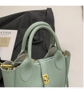 Detailed close-up of light green lychee leather bucket bag with gold zipper and handle