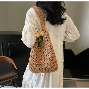 Détail d'un sac cabas en crochet kaki avec des motifs ajourés complexes et une longue bandoulière
