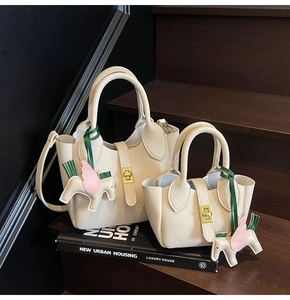 Détail de sacs seaux en cuir crème avec fermoirs dorés et breloques pégase