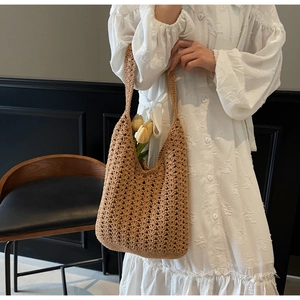 Détail du sac cabas en maille creuse tissé main marron avec accents floraux sur robe blanche
