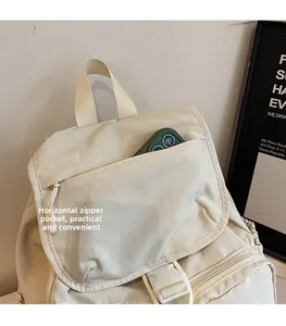 Detailed macro view of the front zipper pocket on a lightweight beige outdoor travel backpack