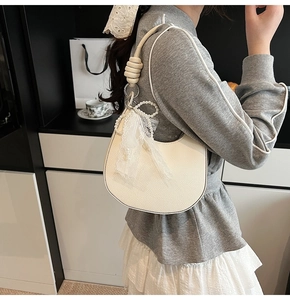 Dettaglio borsa hobo in pelle bianca con tracolla a nodo e fiocco di perle e pizzo