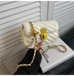 Détail d'un sac bandoulière matelassé blanc avec surpiqûres en V et chaîne dorée