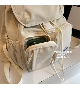 Detailed view of the vertical zipper pocket on beige backpack holding a smartphone