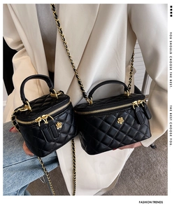 Close-up of black quilted leather box bags with golden camellia logo and chain straps