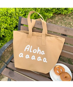 Close-up of khaki canvas tote bag with Aloha print on wooden bench in natural sunlight
