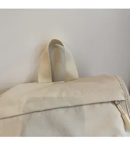 Detail of nylon backpack top handle with reinforced stitching and smooth zipper puller