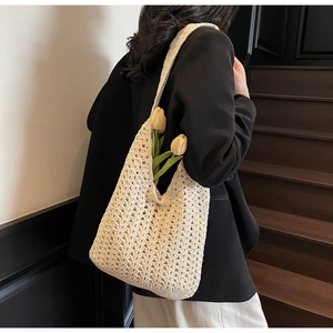 Détail du sac cabas en maille crème montrant la texture ajourée sur l'épaule du mannequin