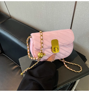 Détail du sac bandoulière rose matelassé avec chaîne dorée et boule décorative