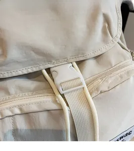 Detail shot of the beige nylon backpack showing secure plastic buckle and swac logo tag