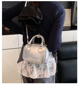 Close-up of silver metallic pillow bag featuring embossed RETRO text and crossbody strap