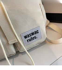 Detail of light beige nylon backpack featuring a purple waswac rules logo patch