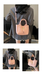Detail view of pink litchi grain leather bucket bag with dual handles and long strap