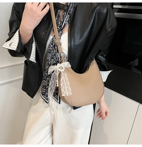 Dettaglio borsa in pelle martellata con pizzo bianco e ciondolo di perle raffinato