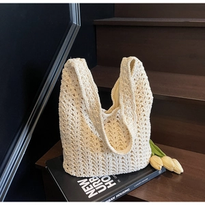 Vue détaillée du sac hobo en crochet crème avec motifs tissés sur fond en bois sombre
