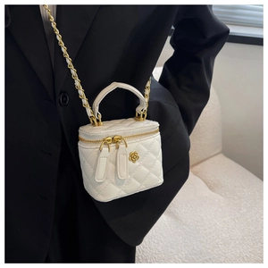 Detail of white quilted leather vanity case with golden camellia metal ornament and chain