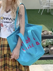 Blue canvas tote bag with pink Aloha print in an outdoor casual aesthetic setting