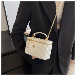 Close-up of white quilted handbag with golden camellia charm and elegant chain strap