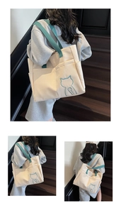 Detail of canvas tote bag with cat pattern showing side pockets and green shoulder strap