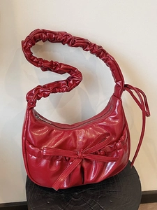 Deep red pleated leather underarm bag with scrunchie strap and ribbon bow decoration