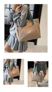 Detail of canvas tote bag with cat embroidery and vintage green straps shown on model