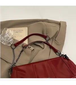 Detail of burgundy leather tote bag with silver chain strap on a khaki trench coat