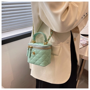 Detailed side view of light green quilted box bag with golden chain strap and floral charm