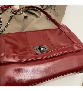 Close-up of wine red patent leather tote with silver metal twist lock and chain strap