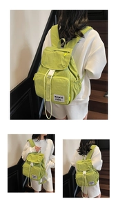 Detail view of light green outdoor backpack showing front zipper pockets and flap buckle closure