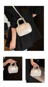 Detail showing retro embossed text on high-gloss cream leather handbag with handle
