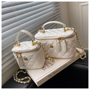 Detail of white quilted vanity bags in two sizes with gold floral zipper and chain straps