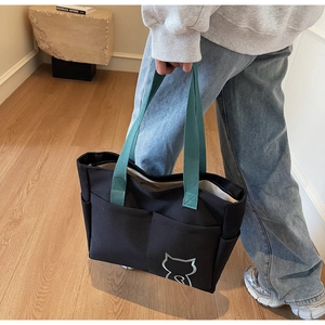 Detail of a large canvas tote bag with blue handles and silver cat print in home setting