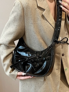 Chic black pleated crescent underarm bag in glossy patent leather with bow decoration