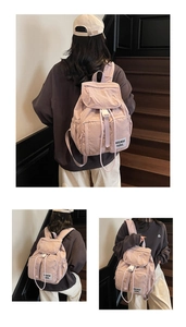 Detail view of pink nylon backpack featuring multi-pocket design and drawstring closure