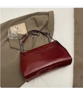 Detailed close-up of dark red glossy leather tote bag with stylish metal chain strap