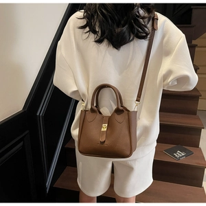Close-up of brown litchi pattern leather bucket bag with metal lock and branding