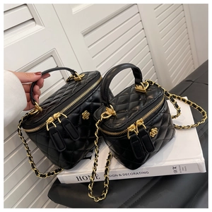 Detail of black quilted leather vanity cases with gold chain and floral metal hardware