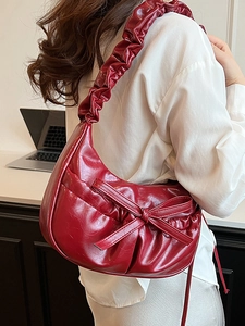 Fashionable dark red pleated underarm bag with bow detail and glossy faux leather finish