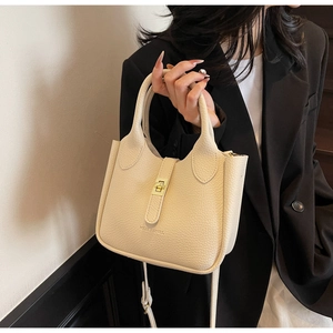 Detailed close-up of cream-white bucket bag with lychee texture and gold clasp