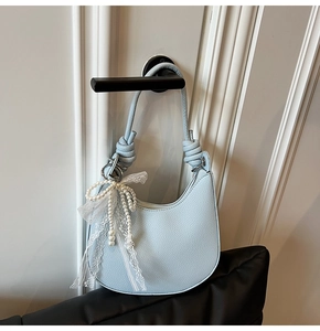 Dettaglio della borsa hobo azzurra con trama litchi ed elegante ciondolo fiocco di perle