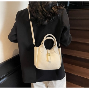 Crossbody view of a cream lychee pattern mini bucket bag with adjustable strap
