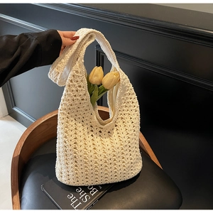 Détail d'un sac cabas en crochet crème avec motifs ajourés posé sur une chaise noire