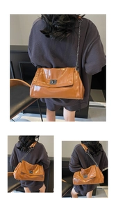 Close-up of brown glossy tote bag with metal chain strap and turn-lock closure detail