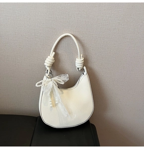 Dettaglio della borsa hobo bianca con trama lychee, ciondolo in pizzo e perle e manico annodato